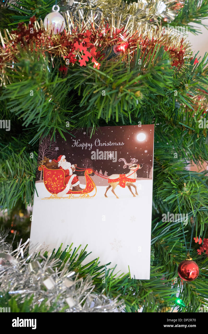 Christmas card between branches of a Christmas tree surrounded by tinsel Stock Photo