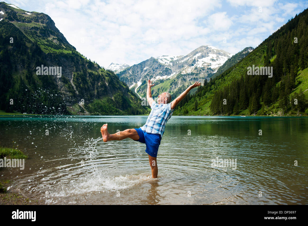 Mature man standing in lake, kicking water, Lake Vilsalpsee, Tannheim Valley, Austria Stock Photo
