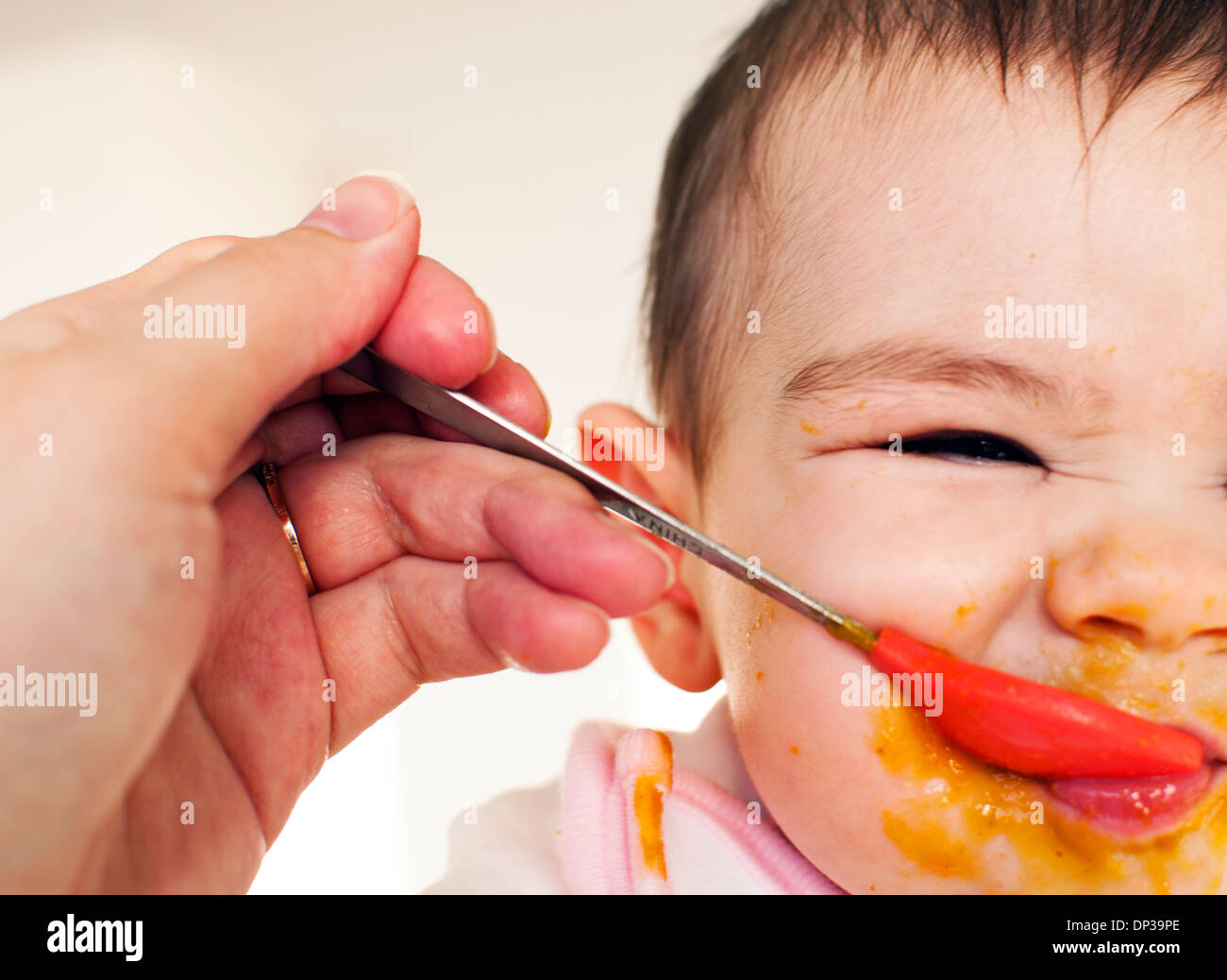 Baby making sour face while eating Stock Photo
