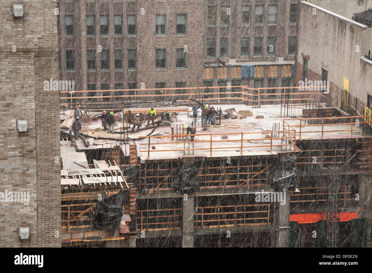 High-rise Building Construction Site with tradesmen in Snow Storm, NYC Stock Photo
