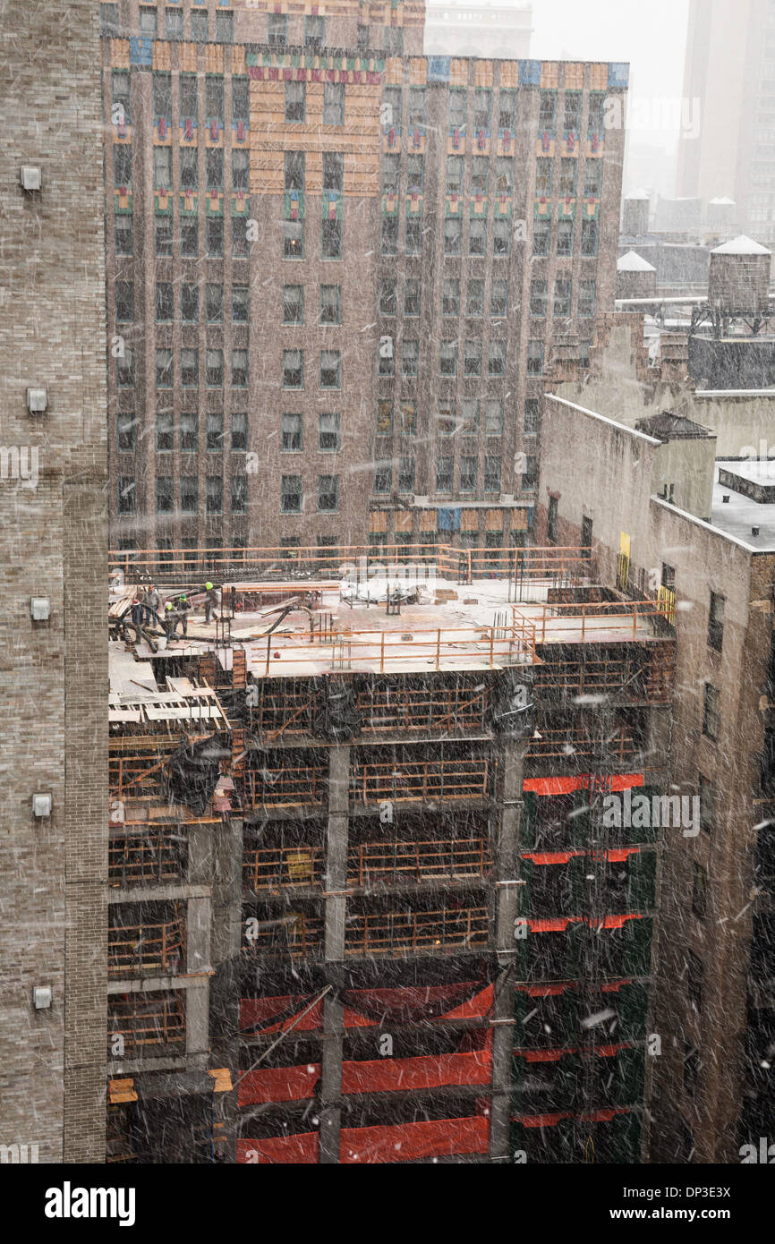 High-rise Building Construction Site with tradesmen, in Snow Storm,  NYC Stock Photo