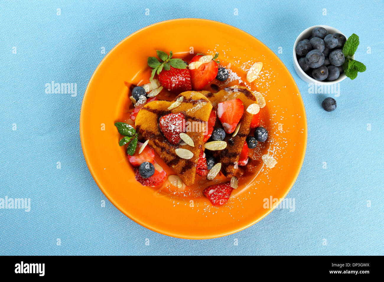 Two pancakes hearts with strawberry, almond slivers, blueberries, top view Stock Photo