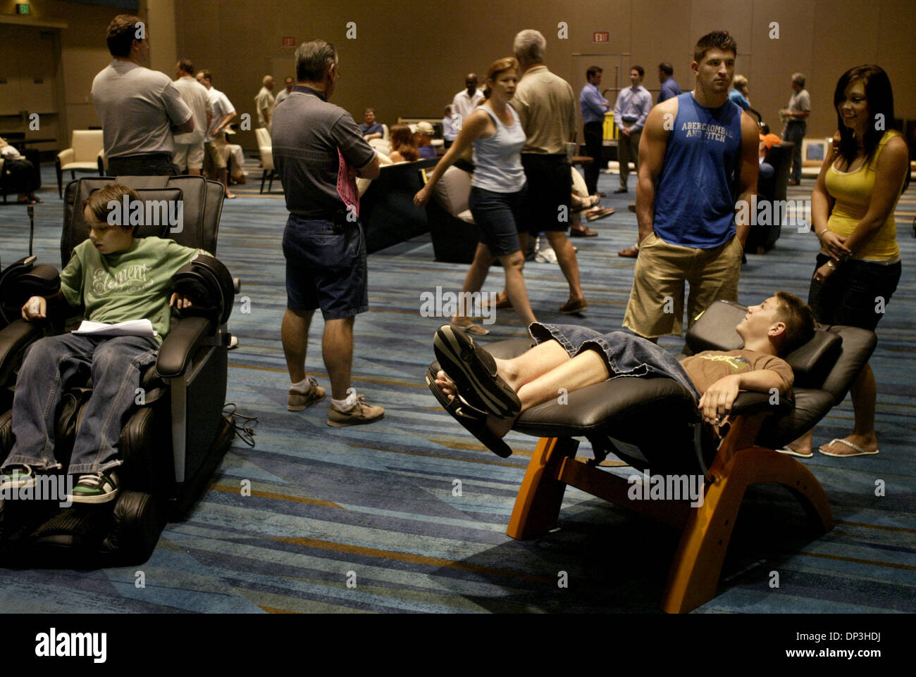 Jul 08, 2006; West Palm Beach, FL, USA; Mark Cooney (right, in chair) checks out a leather chair for sale during an auction at the Palm Beach County Convention center.  Behind him are his brother, Peter, and his brother's girlfriend, Kristen Sonntag.  Mark and Peter's mom were hoping to buy a flat screen television at the auction.  At left, Andrew Nelson sits in a chair called the  Stock Photo