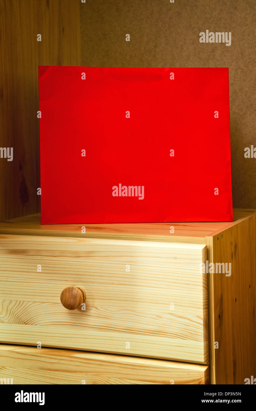 Red shopping bag in wooden beech cabinet. Stock Photo