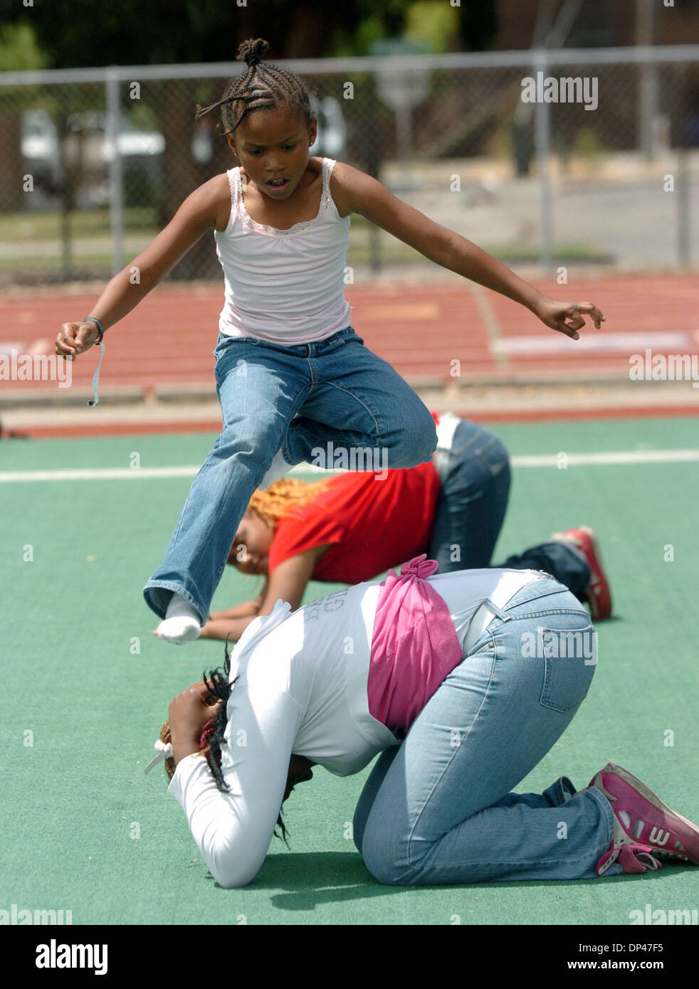 Jul 29, 2006; San Pablo, CA, USA; AMANDA POLK, 8, jumps over RAYSHELL DAVIS at the the BSAA (Black Sports Agents Association) sports and dance clinic at Contra Costa College. The clinic, thrown by Andre Farr, a former Kennedy High School and UCLA football player, featured motivational speakers and professional coaches giving instruction in basketball, football and dance among other Stock Photo