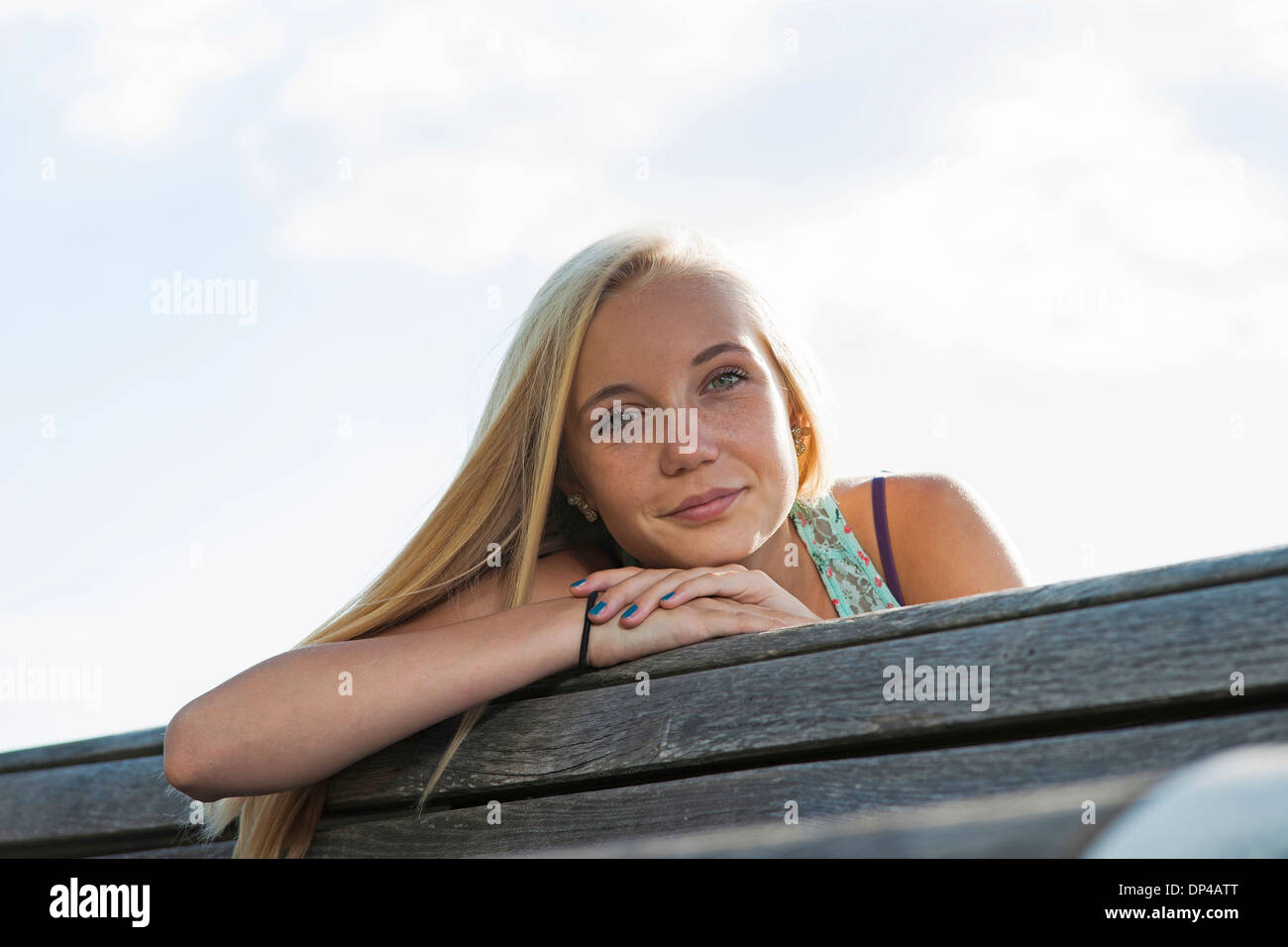 Portrait of teenage girl sitting on bench outdoors, looking at camera, Germany Stock Photo