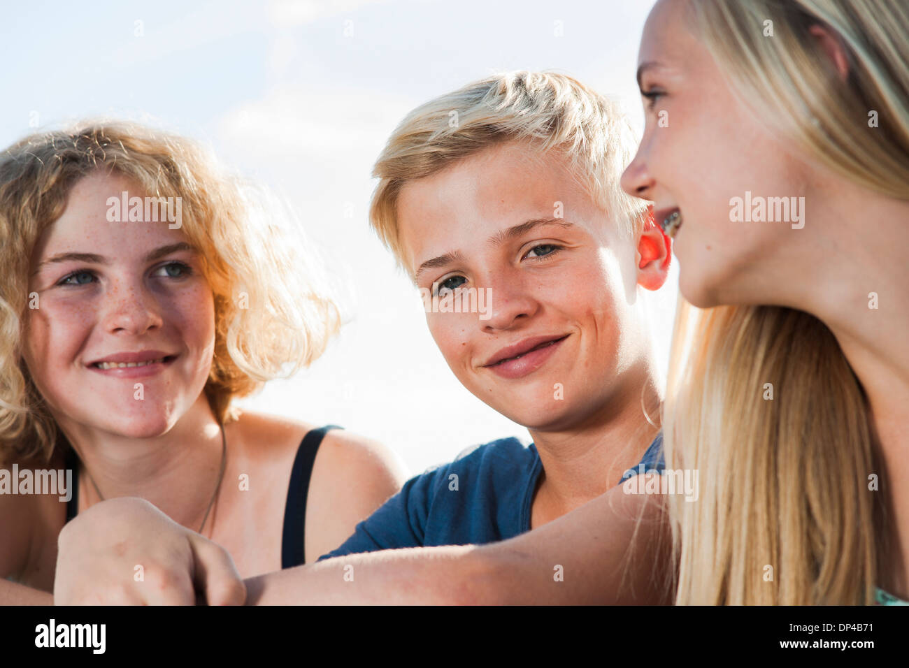Close-up portrait of teenage girls and boy sitting outdoors, Germany Stock Photo