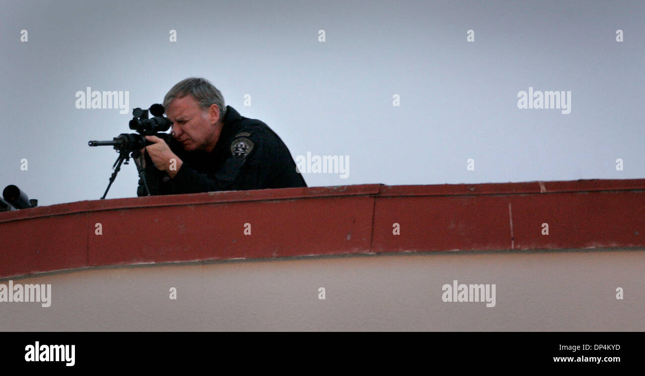 Aug 17, 2006; San Diego, CA, USA; A San Diego Police SWAT team member watches the activity below from a hanger at the San Diego Coast Guard Station surrounding the transfer from a Coast Guard vessel of members of the Arellano-Felix drug cartel to waiting DEA SUVÕs. The suspects, as many as 11 were arrested in international waters off the coast of Baja California on Monday August 14 Stock Photo