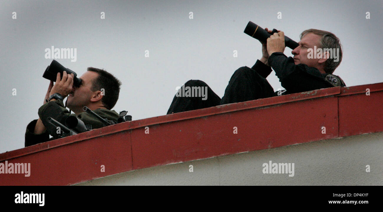 Aug 17, 2006; San Diego, CA, USA; Two San Diego Police SWAT team members watch an aircraft from the top of a hanger at the San Diego Coast Guard Station. They were part of the transfer from a Coast Guard vessel to DEA SUV's of members of the Arellano-Felix drug cartel. SUVÕs. The suspects, as many as 11 were arrested in international waters off the coast of Baja California on Monda Stock Photo