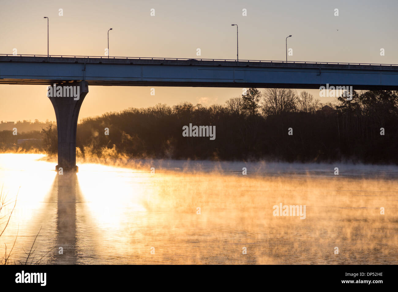 The sunrise silhouettes the Veterens' Bridge as steam rises from the Tennessee River on a very cold winter morning Stock Photo