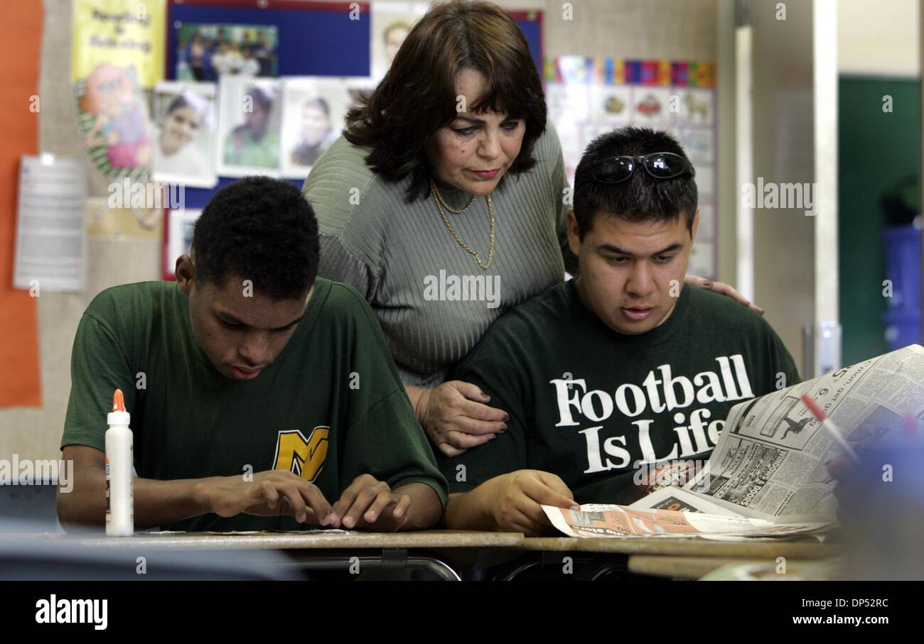 (Published 3/10/2005, B-7:6) NC MARVISTA 235853 x006 ............... 1 March, 2005, ImperiaL Beach ............  Marianne Amador (cq, teacher, center) shows looks over the shoulders of her students Nathaniel (cq) Arnold (left, age20) and Alan Calderon (cq, age18, right)  as the two students put together a visual packing list made from newspaper and magazine clippings of what to pac Stock Photo