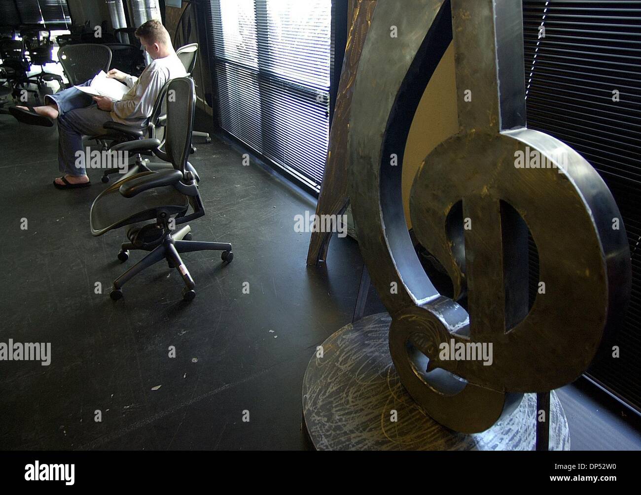 (Published 3/9/2004, C-6, UTS1793791) Con Reilly (left) of the DIVX company, goes through a list of the items up for bid next to a piece of artwork in the shape of a musical note in the former office spaces of the now-defunct MP3.COM company.  Earnie Grafton/UT Stock Photo
