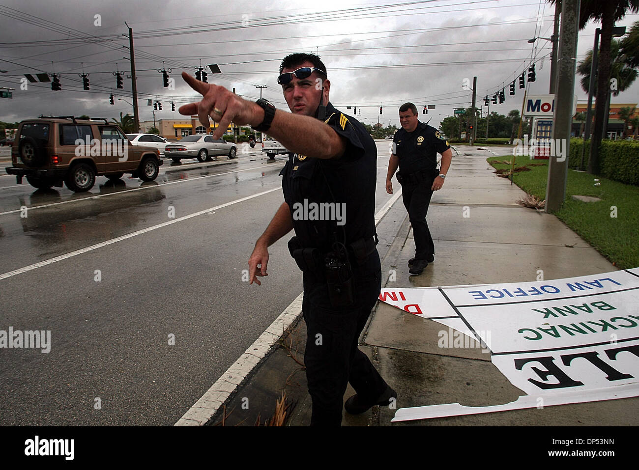 Aug 30, 2006; Boynton Beach, FL, USA; Boynton Beach Police Sergeants Steve Wessendorf (cq), left, and Stewart Steele (cq) try to figure out where a windblown sign came from on Congress Ave. at  Boynton Beach Blvd. in a driving rain Wednesday morning, Aug. 30, 2006. The Department expected much more activity, the worst of which would come from Tropical Storm Ernesto, and removing th Stock Photo