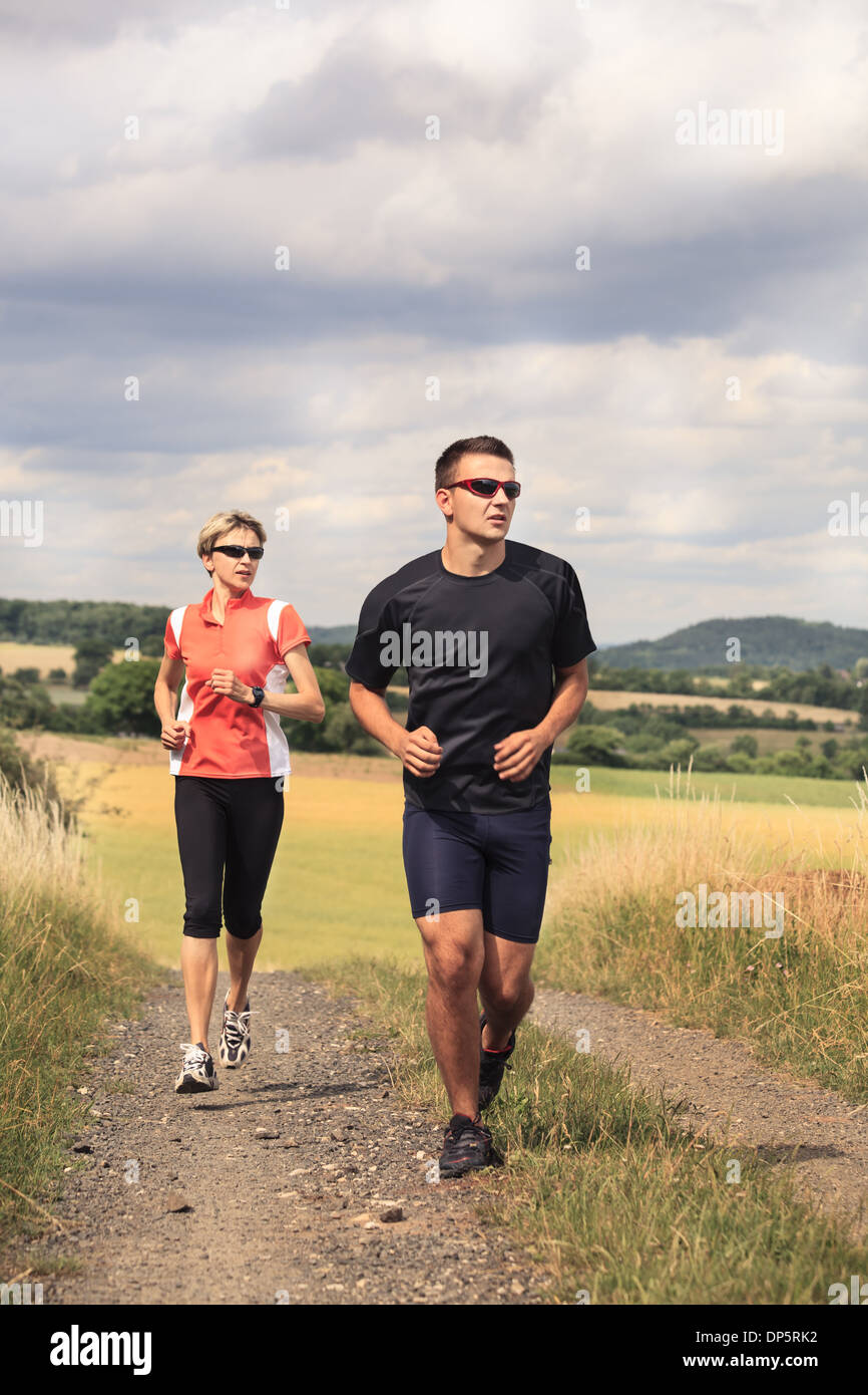 people jogging on the road in front of rural landscape Stock Photo