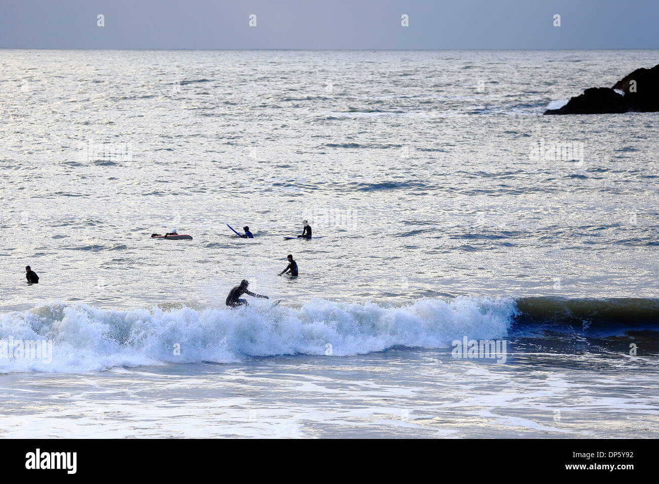 A surfer sihouetted against the sea, rides the waves Stock Photo