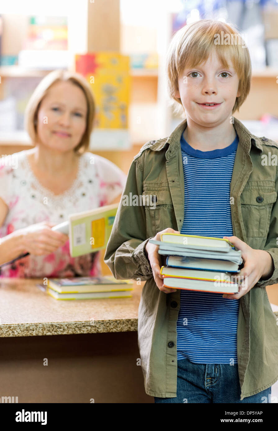 Schoolboy Checking Out Books From Library Stock Photo