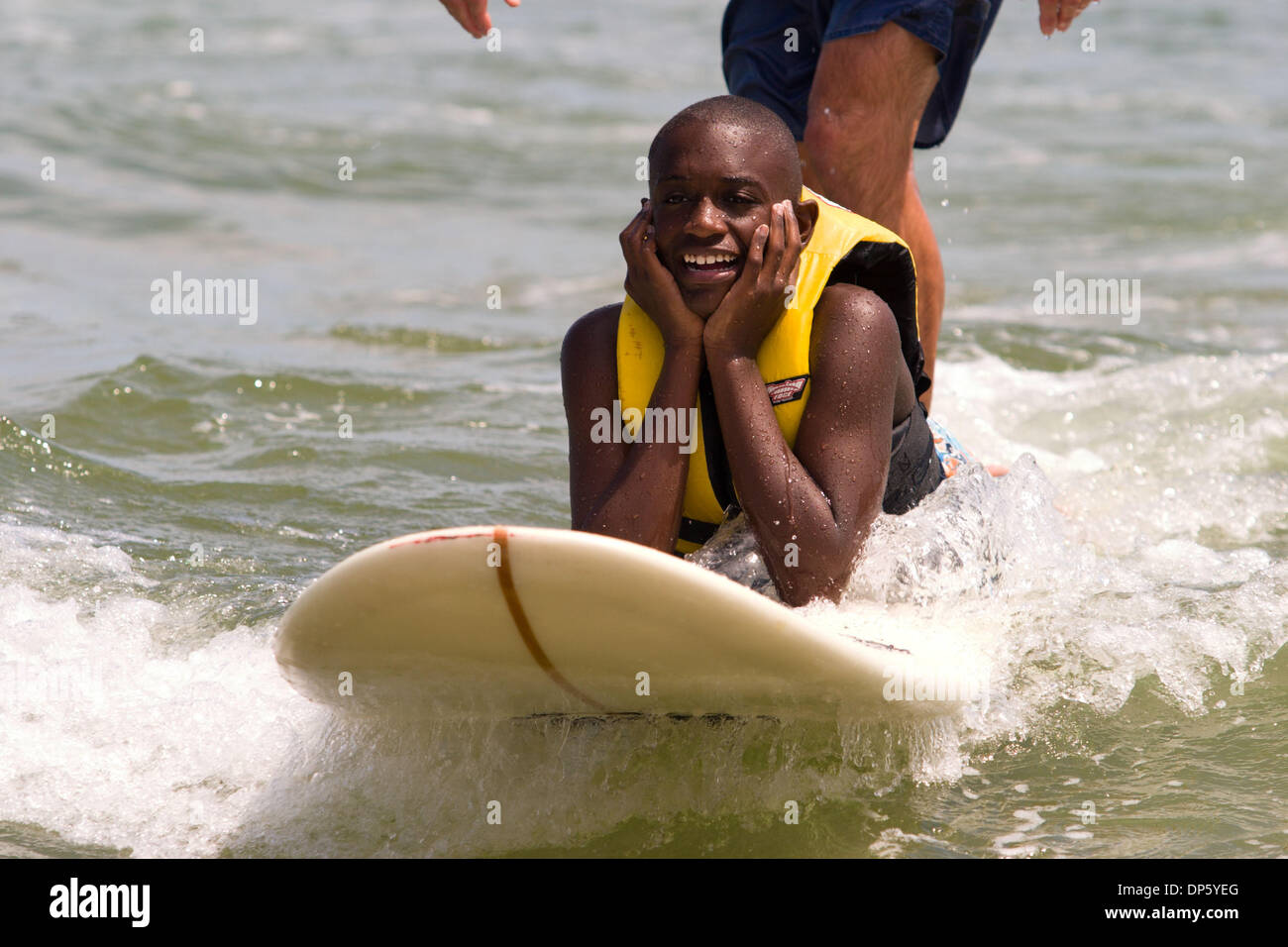 Aug 29, 2006; Virginia Beach, VA, USA; Johnie and Madgeline Hamilton loved watching their thirteen year old son Darius ride the waves into shore. Darius, who is considered severe on the Autism spectrum, did stand up on the board, but chose to lie down on his belly with his head in his hand. It was evident that he loved surfing by the huge smile on his face and how many times he wen Stock Photo