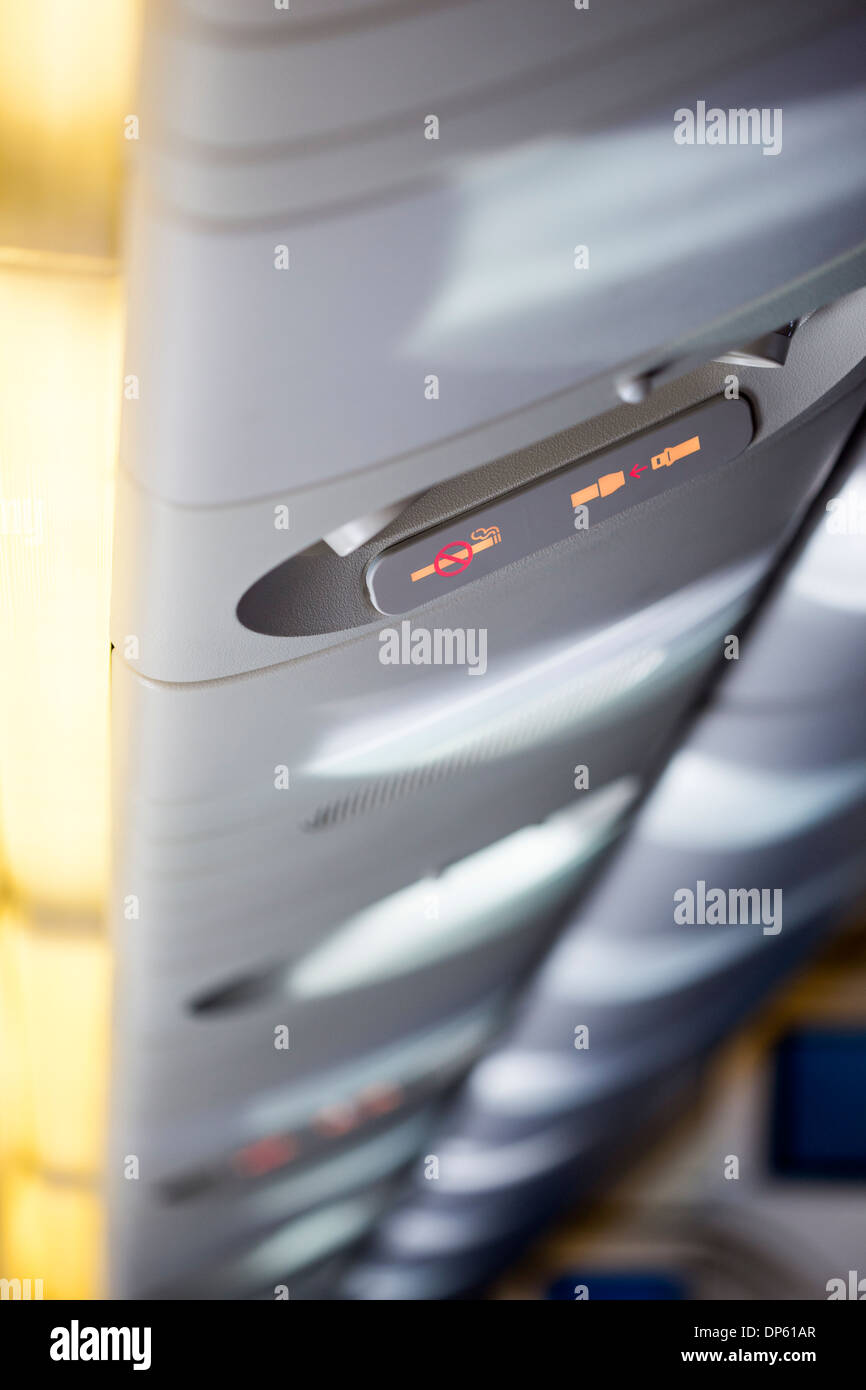 Close-up of the illuminated fasten seatbelt and no smoking signs inside an airplane, selective focus on signs. Stock Photo