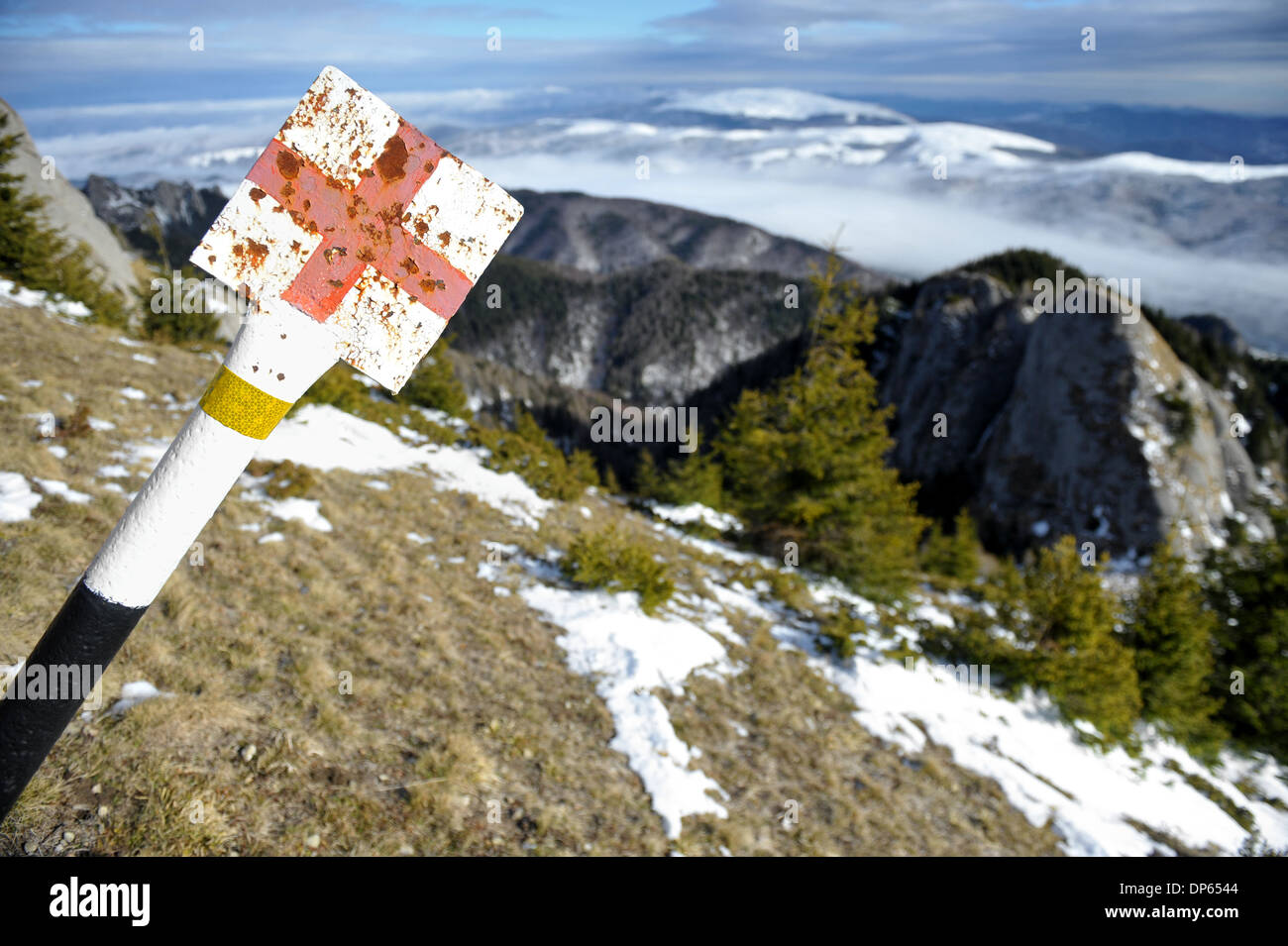 Red cross marking pole on a mountain in early winter Stock Photo