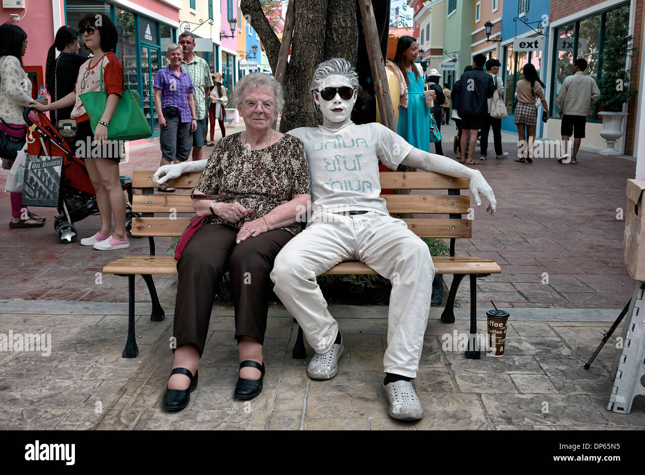 Street Artist entertainer. Senior woman seated with a white painted street entertainer Thailand Asia Stock Photo
