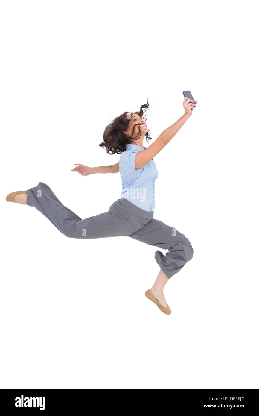Happy classy businesswoman jumping while holding smartphone Stock Photo