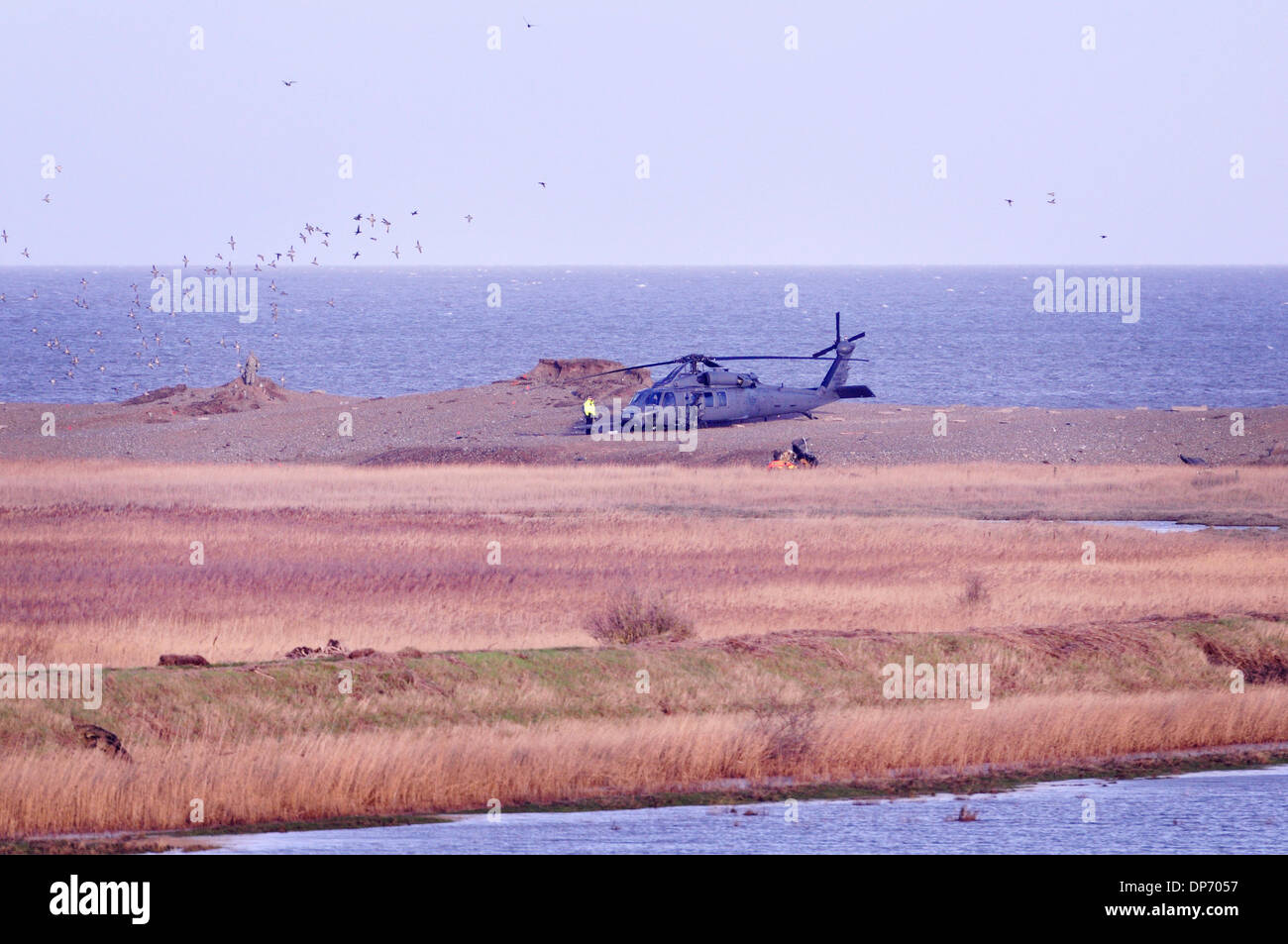 Cley-next-the-Sea, Norfolk, UK. 8th Jan, 2013.  Pave Hawk crashed 8pm 7th January 2014 on shingle bank. Crew of four dead.  An intact accompanying aircraft sits on the shingle with wreckage of the lost aircraft just visible this side of i Credit:  John Worrall /Alamy Live News Stock Photo