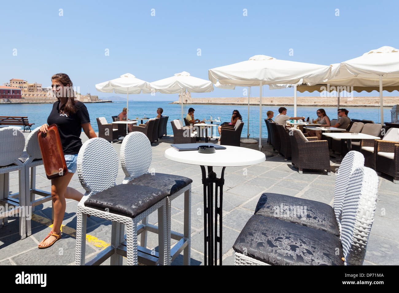 People enjoying in a restaurant cafe pub at the ancient Venetian harbor of Chania, Crete Island, Greece Stock Photo