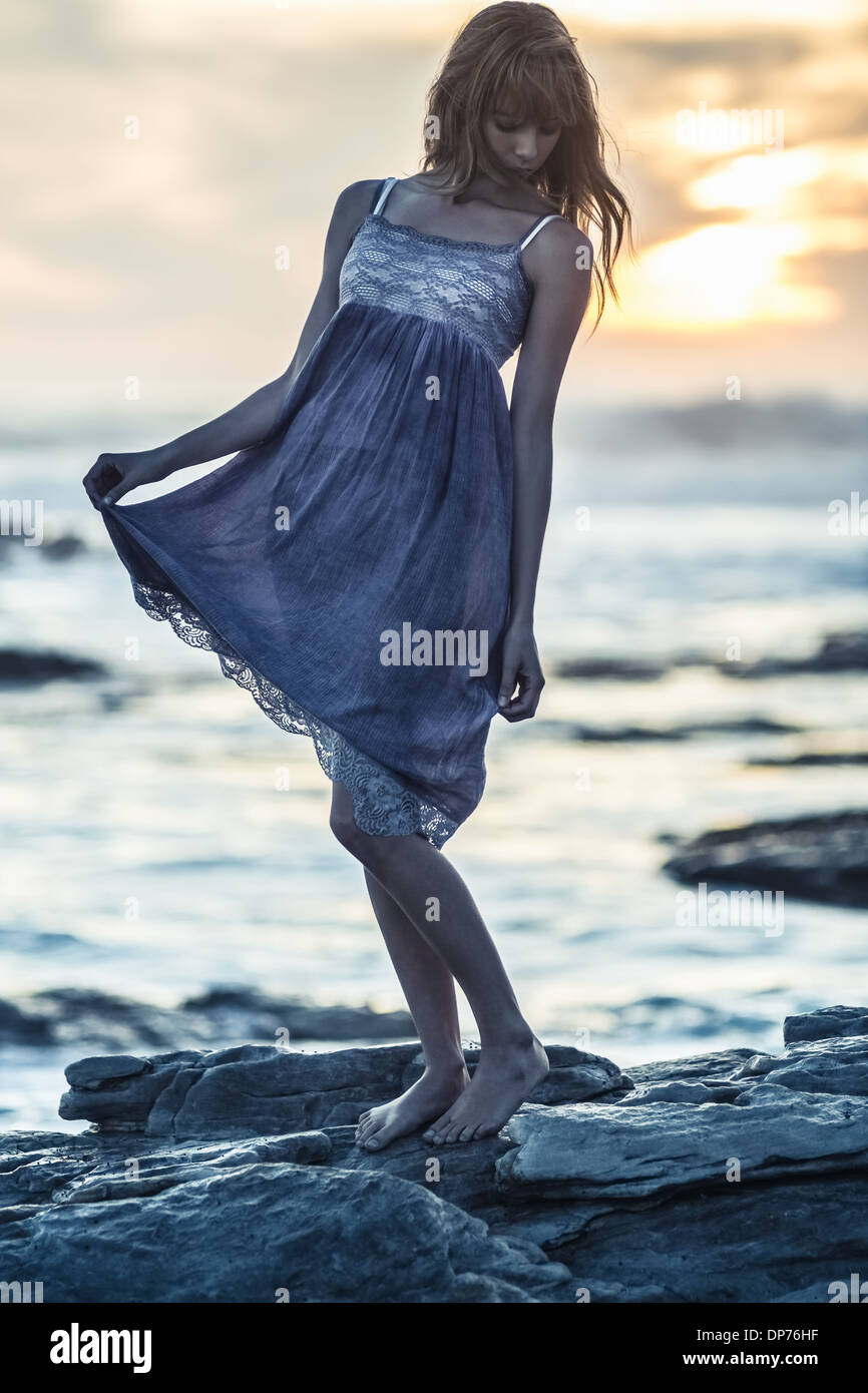Beautiful young woman standing on rocks by the sea Stock Photo - Alamy