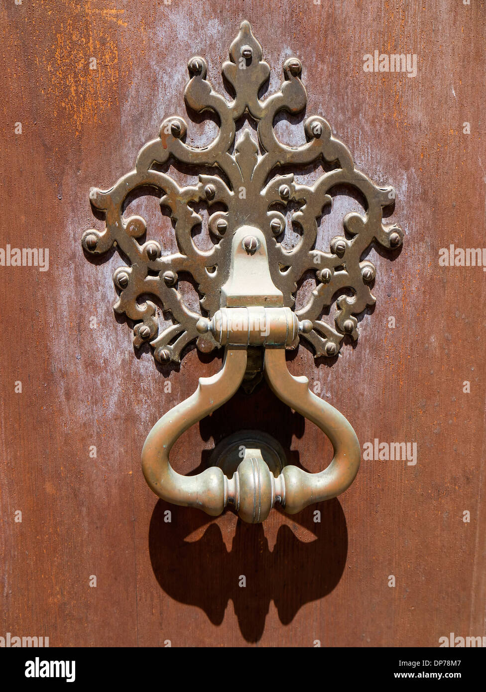 Ornate bronze door knocker on a rustic door Stock Photo