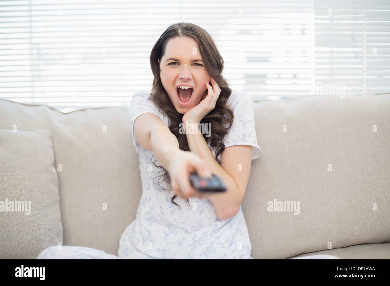 Scared young woman changing tv station Stock Photo