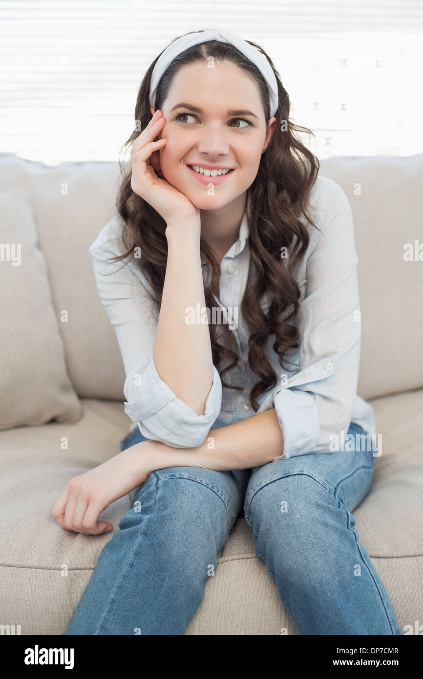 Cheerful casual woman sitting on a cosy couch Stock Photo - Alamy