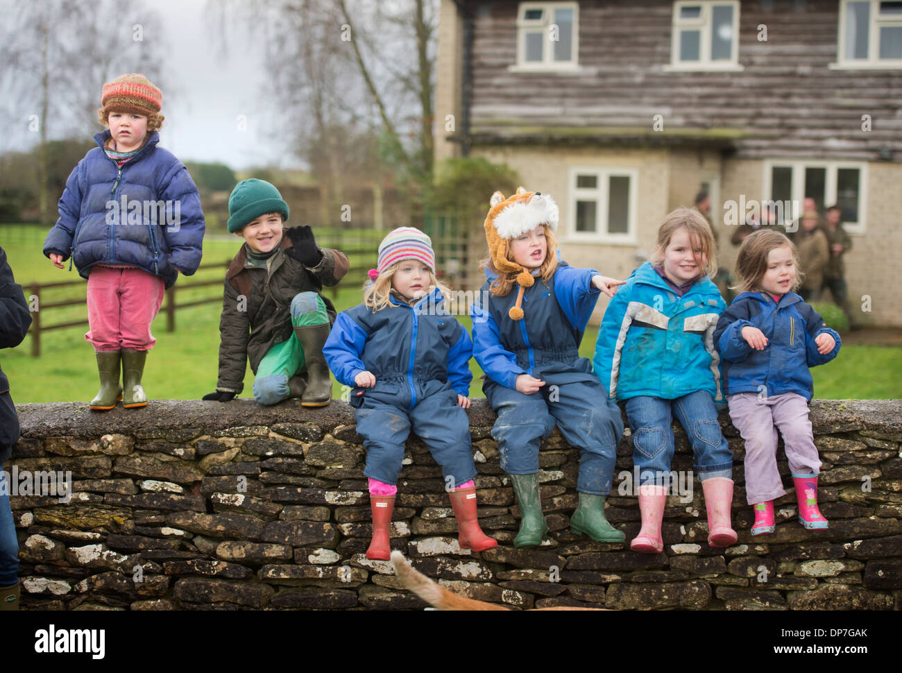 A group of country children sitting on a Cotswold stone wall at a meeting of the Beaufort Hunt in Didmarton, Gloucestershire UK Stock Photo