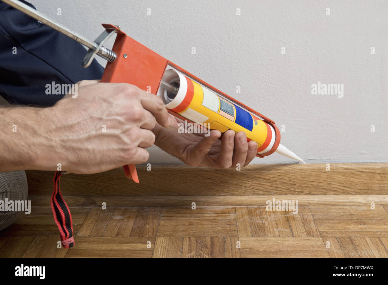 Caulking silicone from cartridge on wooden batten. Stock Photo