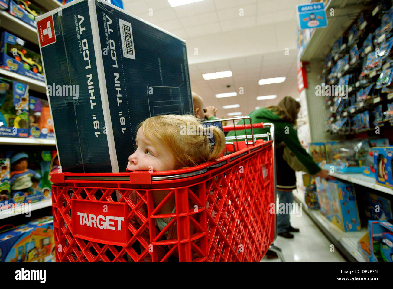 Nov 22, 2006; Encinitas, CA, USA; MOLLIE SOWARDS, age 3, sinks into a corner of her mother's Target shopping cart at 6:31 a.m., as her mother, MICHELE SOWARDS, age 32 of San Marcos, right, shows a toy to her 6-year-old son, SAM.  Early risers shop at Target Greatland store in Encinitas Friday, the day after Thanksgiving.  Many lined up for deep discounts on certain items that were  Stock Photo