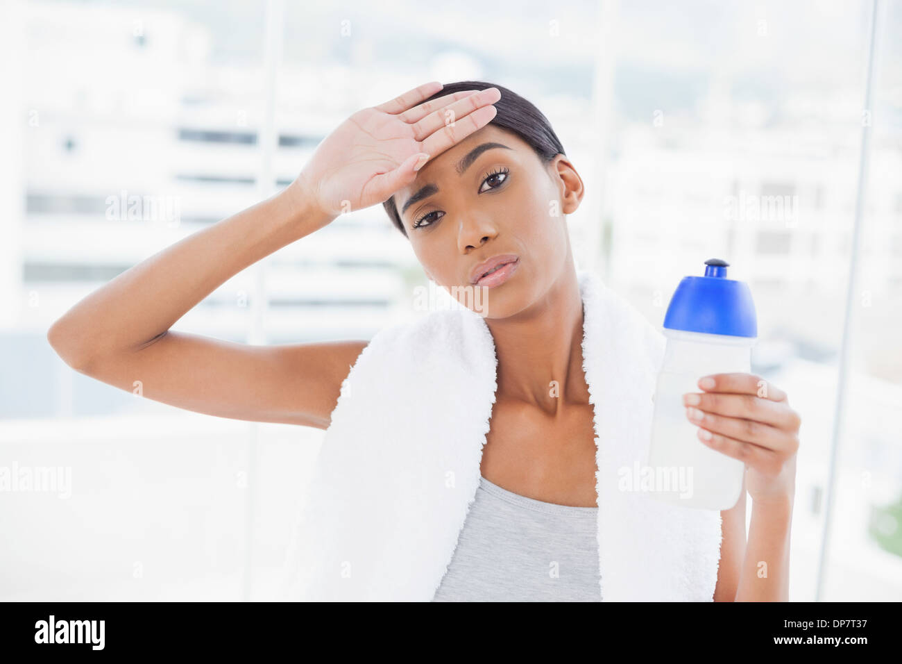 Exhausted sporty model wiping her forehead after exercising Stock Photo