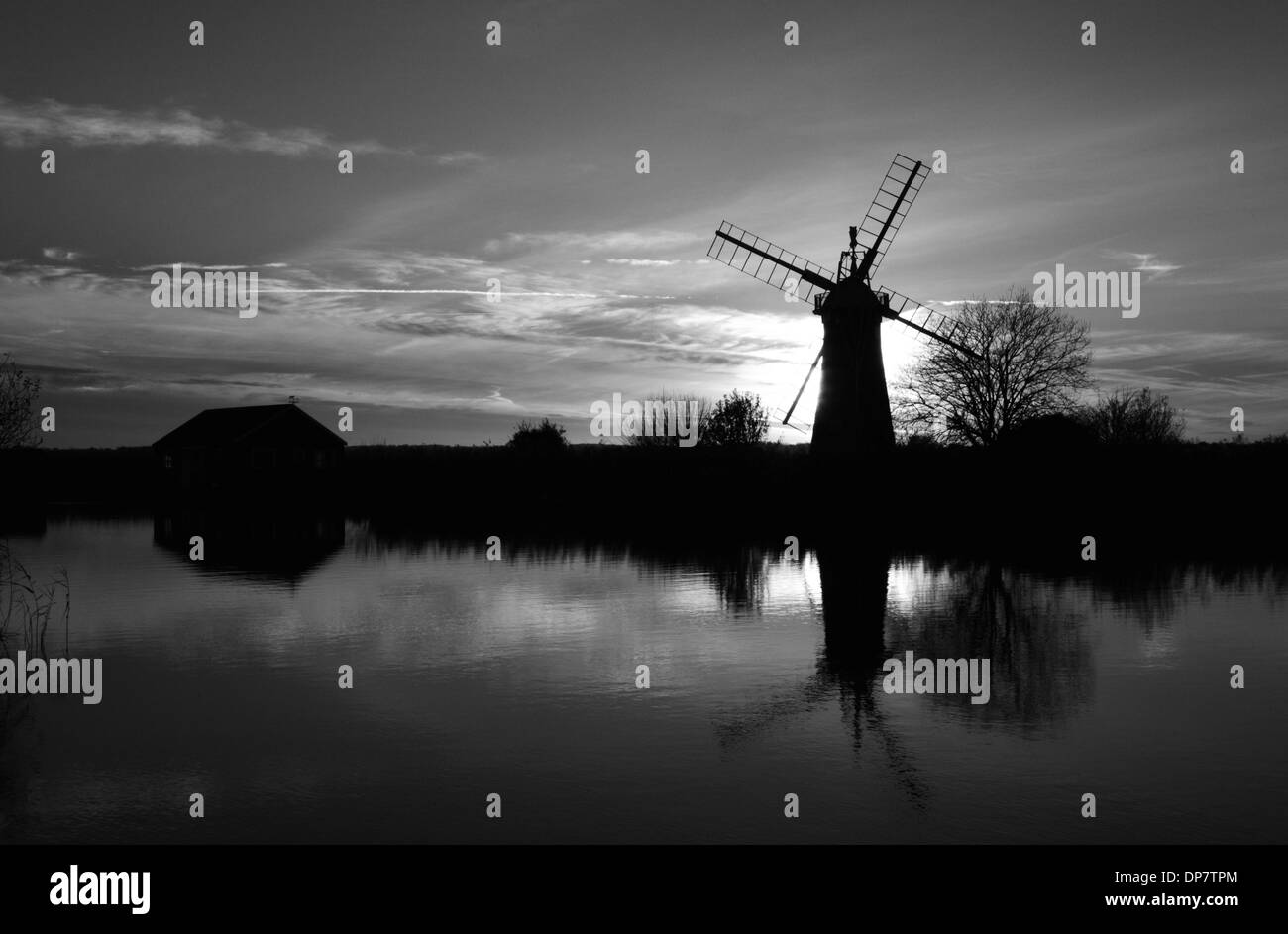 A monochrome view of a windmill and sunset with reflections by the River Thurne on the Norfolk Broads, England, United Kingdom. Stock Photo