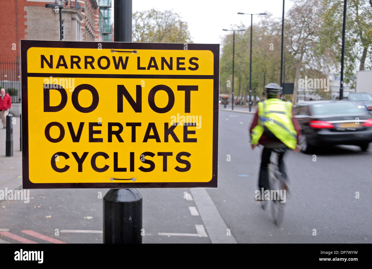 A cyclist passes a new 'Do Not Overtake Cyclists' road sign, Westminster, London, UK, December 2013. Stock Photo