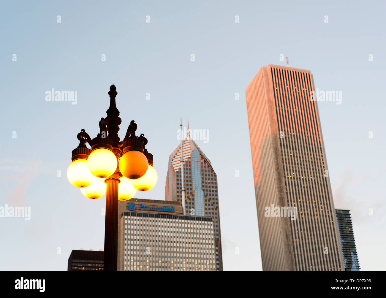 Illuminated old style street light with modern buildings beyond. Stock Photo