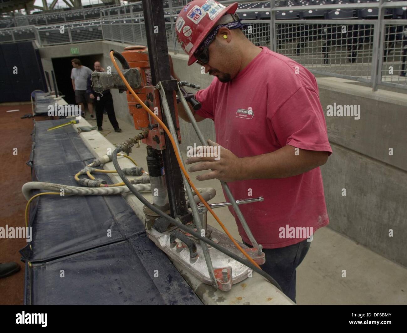 (Published 4/7/2004, D-6; UTS1800048) Carlos Aranda of the Penhall Company drills holes in the concrete wall outside the right field at Petco Park Tuesday. A cyclone fence will be added on top of the padding because two players have already gone over the wall chasing down fly balls. Peggy Peattie photo Stock Photo