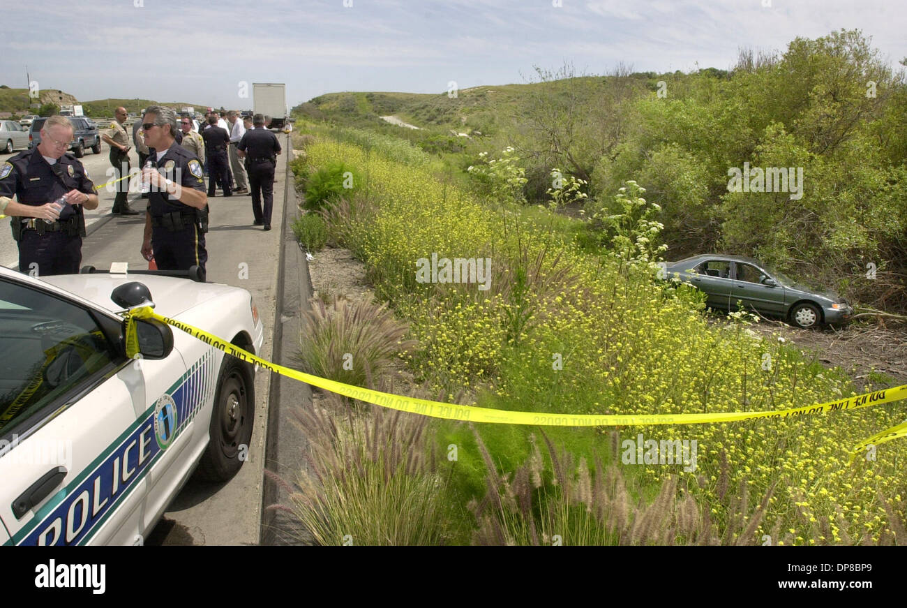 (PUBLISHED 05/02/2003, NC-1): A car that a robbery suspect crashed then shot himself in sits down the embankment off of southbound I-5's right lanes, south of Las Pulgas Rd. on Camp Pendleton. At left are Irvine Police Officers (with one of their cars) who were chasing the suspect.  U/T photo CHARLIE NEUMAN Stock Photo