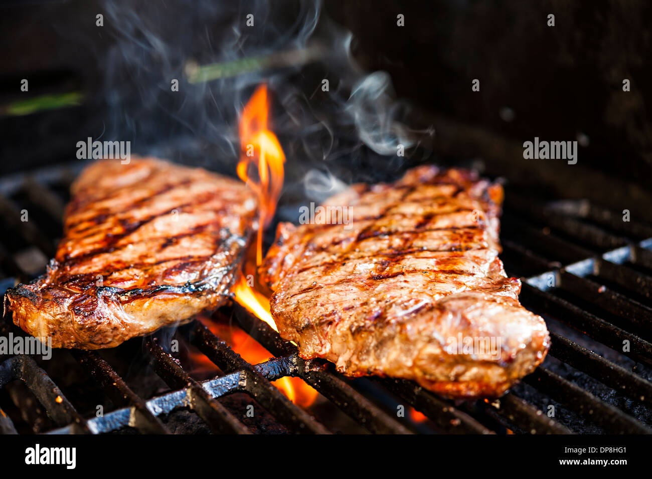 Beef steaks cooking in open flame on barbecue grill Stock Photo Alamy
