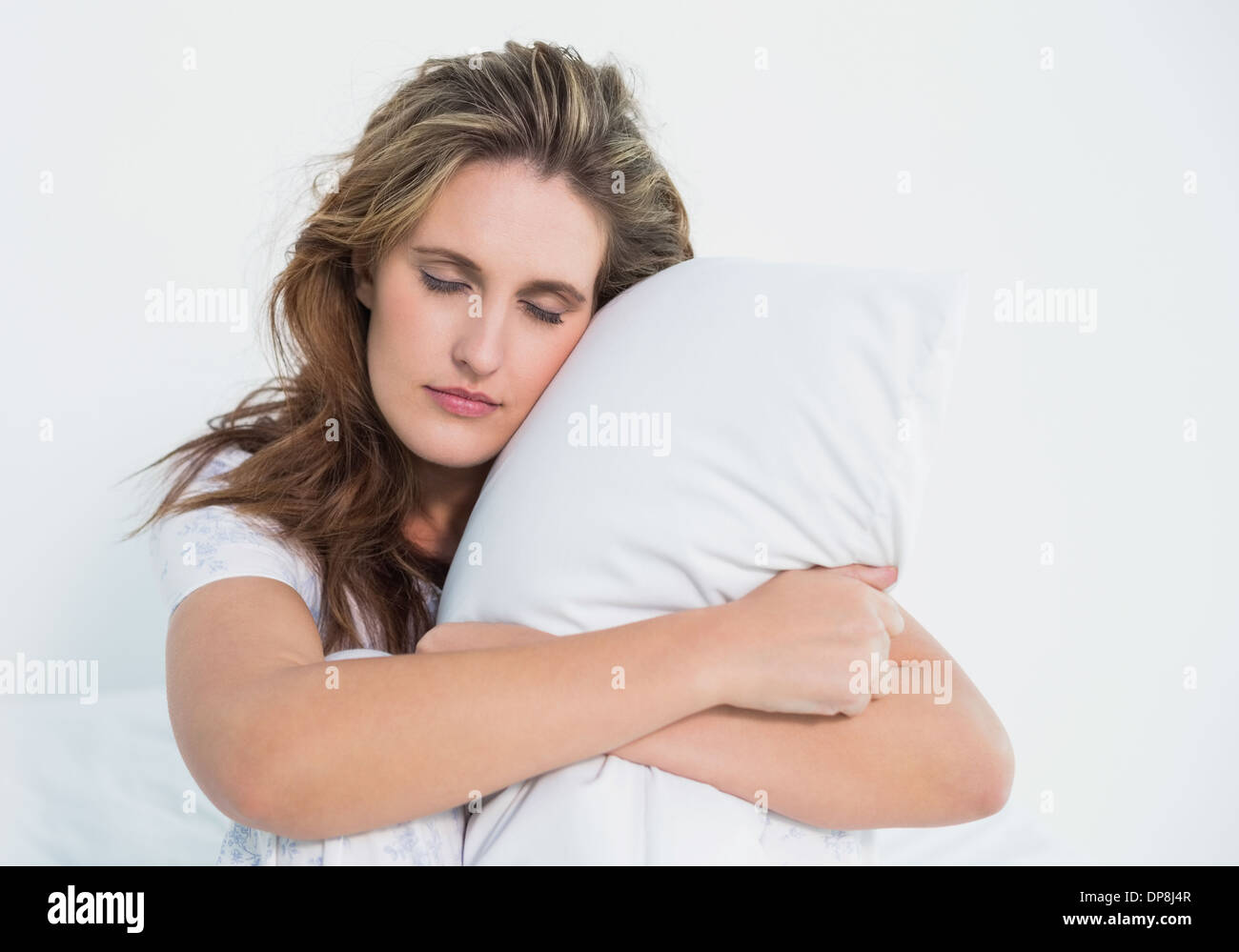 Woman hugging pillow sitting on her bed Stock Photo Alamy