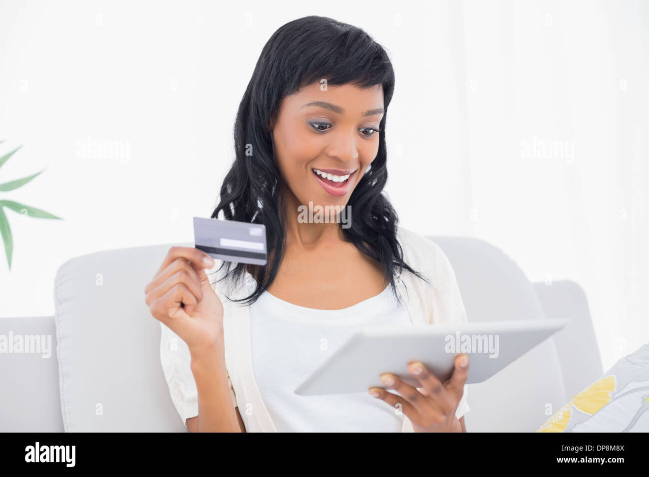 Amazed black haired woman buying online with her tablet pc Stock Photo