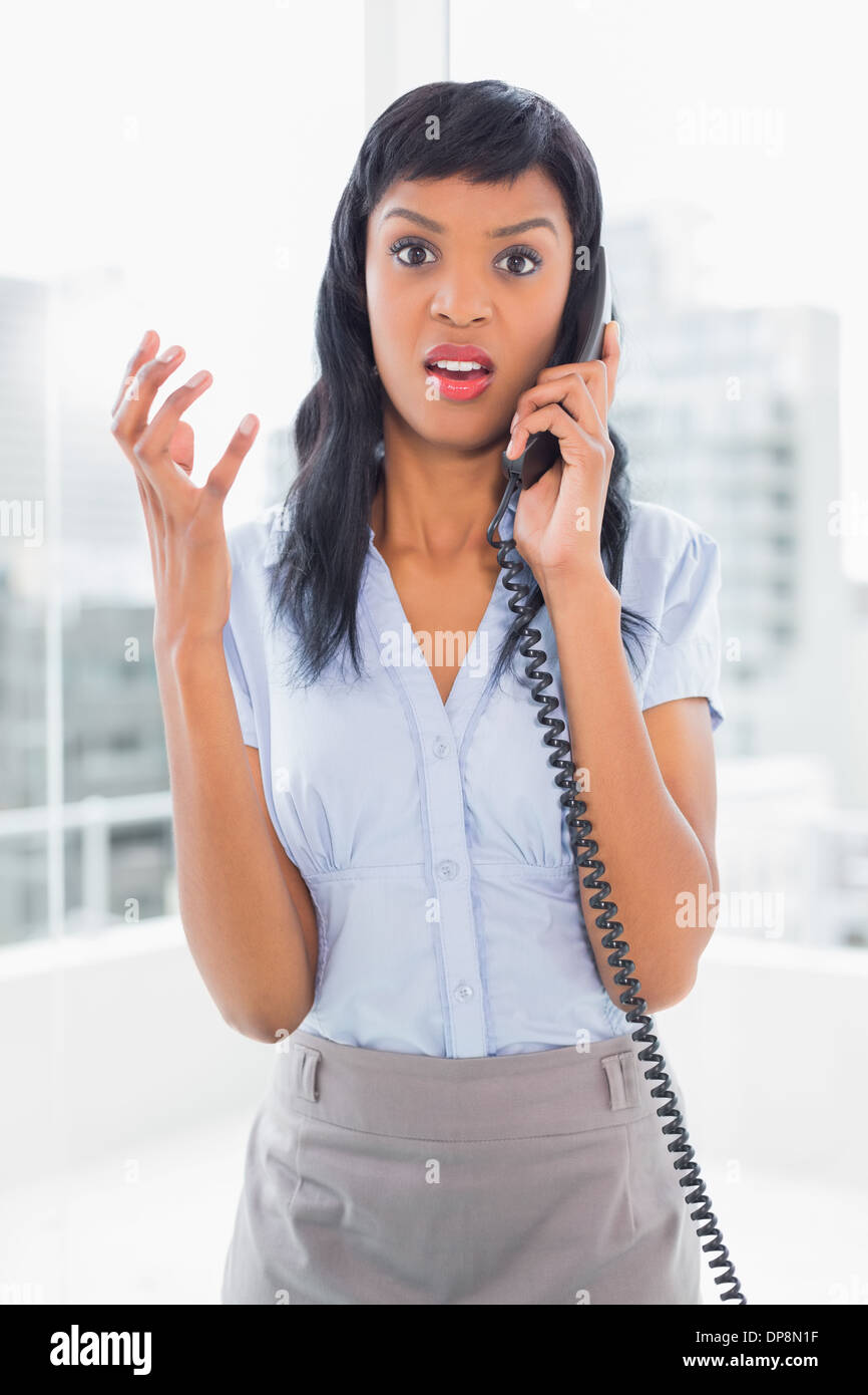 Angry businesswoman answering the phone Stock Photo