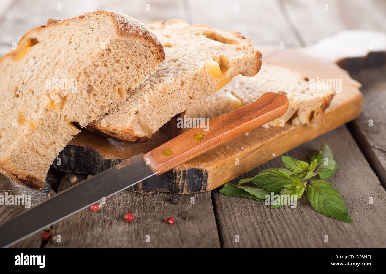 Bread with knife on a cutting board and wooden background Stock Photo