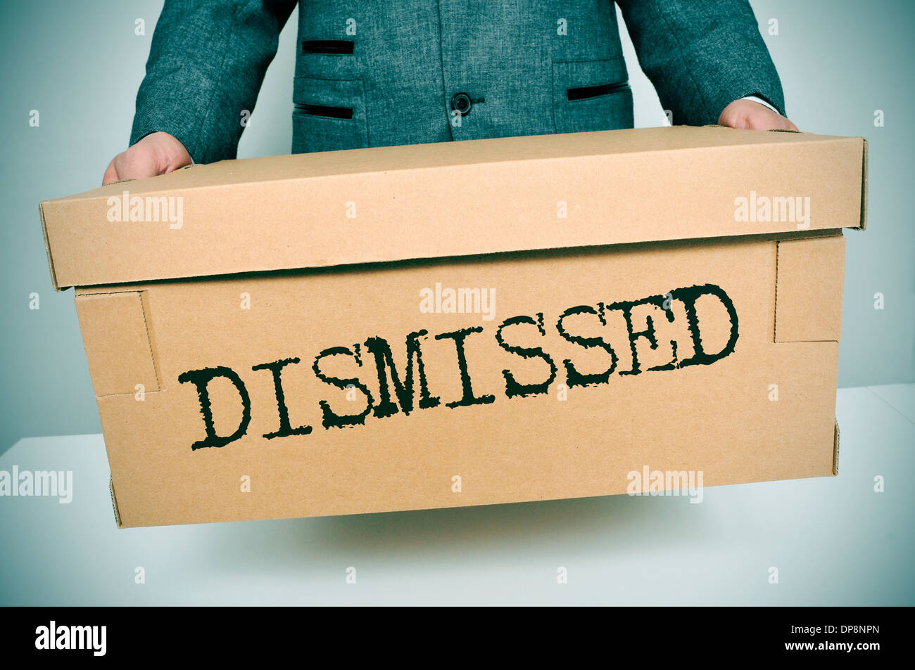 a businessman carrying a box with the word dismissed written in it Stock Photo