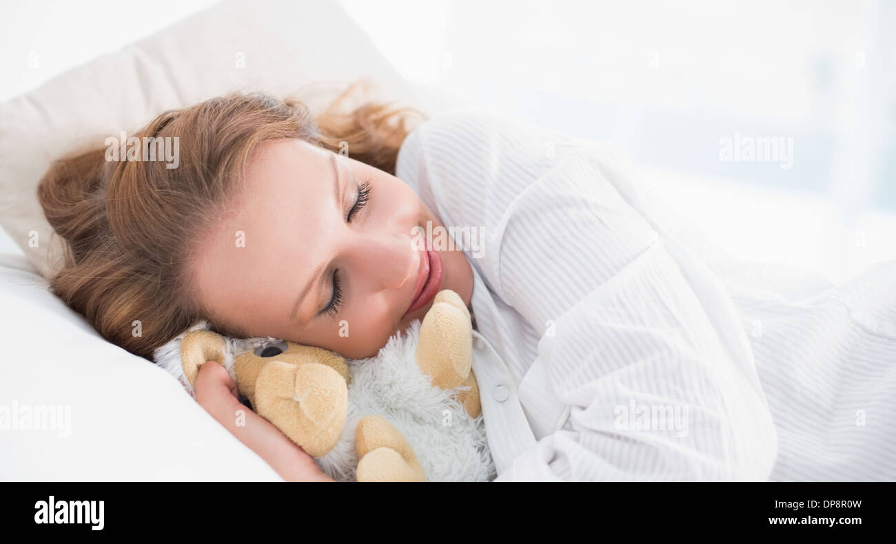 Smiling pretty woman sleeping embracing a plush sheep Stock Photo