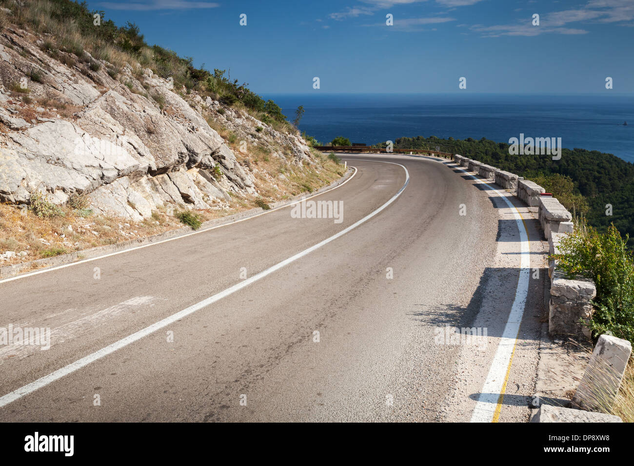 Left turn of mountain highway with blue sky and sea Stock Photo