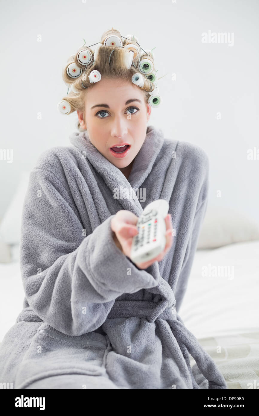 a woman with curlers is hiding something behind her back Stock Photo