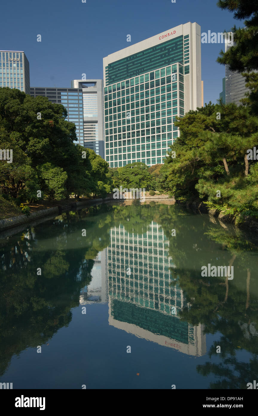 Conrad Hotel reflected in the waters of the Hama Rikyu Teien (Hamarikyu Detached Garden), Tokyo, Japan Stock Photo